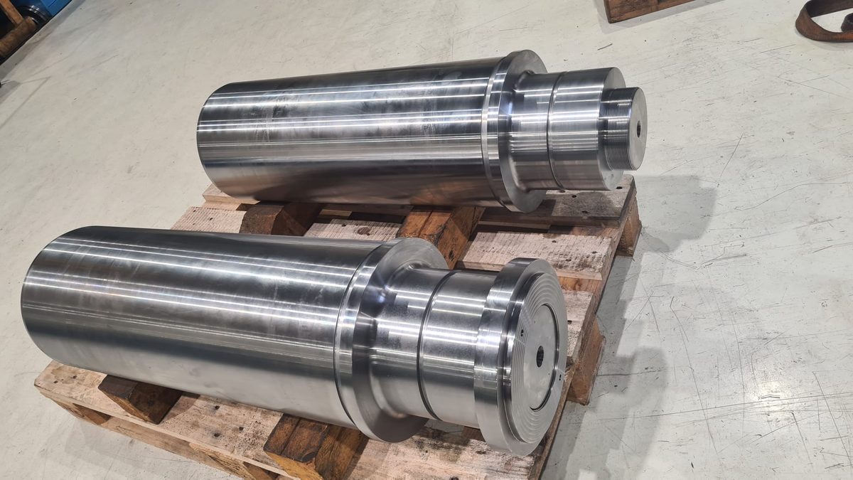 Two heavy shafts machined from forged bar, staged on a pallet for dispatch
