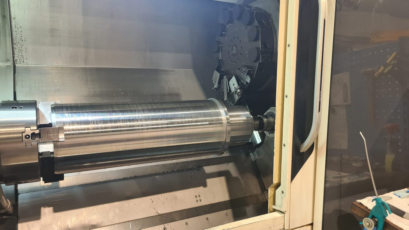 Long steel shaft turned between centres on a heavy horizontal lathe