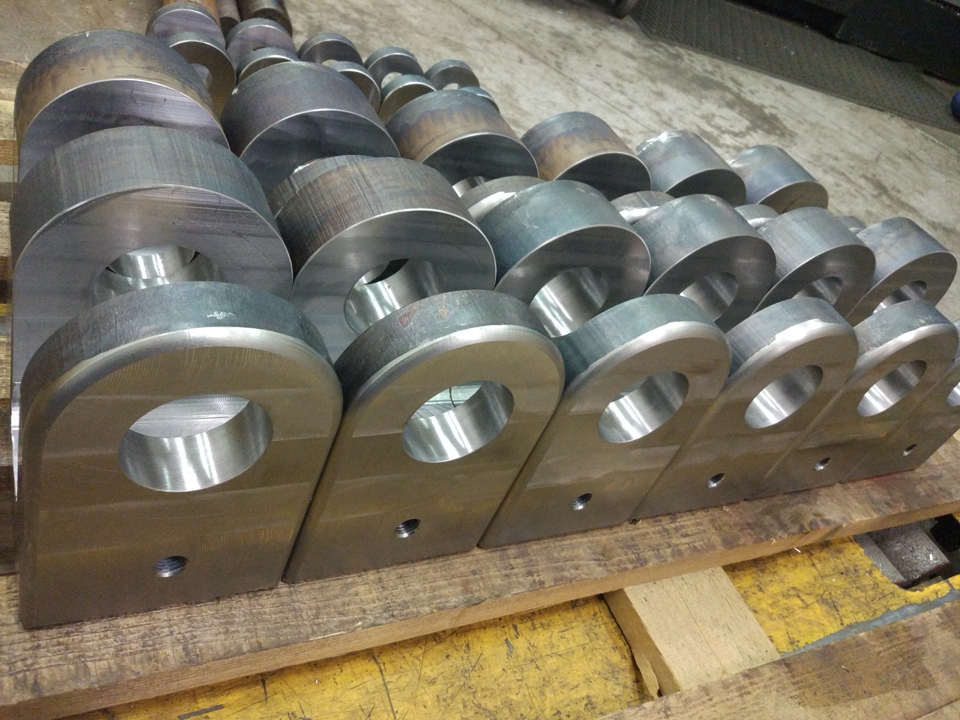 Serial batch of bored and milled heavy steel lugs on a pallet
